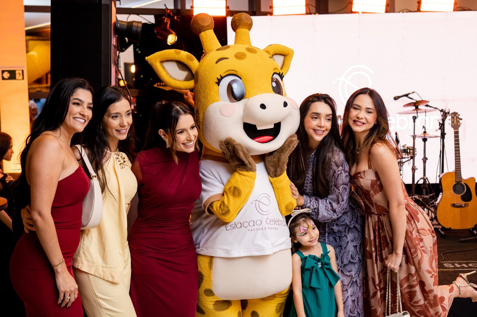 Mascote Lumi com uma criança e convidadas em festa